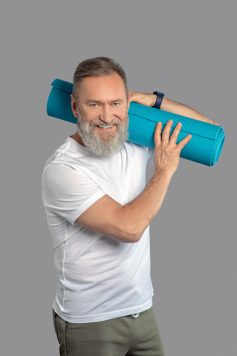 Bearded man holdinga mat for the workout